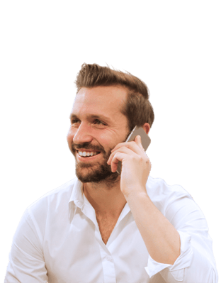 Man met baard glimlacht terwijl hij aan het telefoneren is.