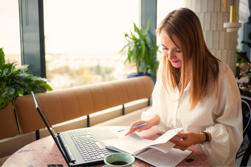 Medewerker volgt een cybersecurity training op op een laptop en maakt aantekeningen in een moderne werkruimte.