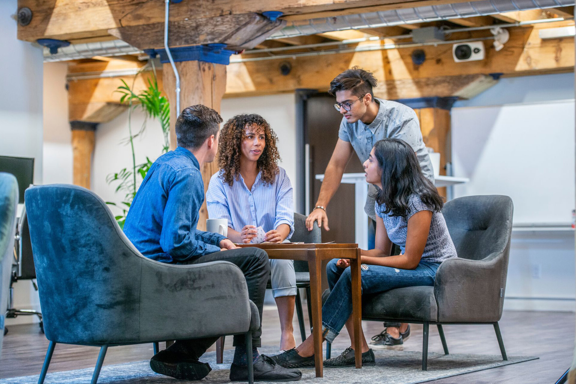 Een klein team van vier collega's in een casual kantoorsetting bespreken het belang van security awareness in hun organisatie.