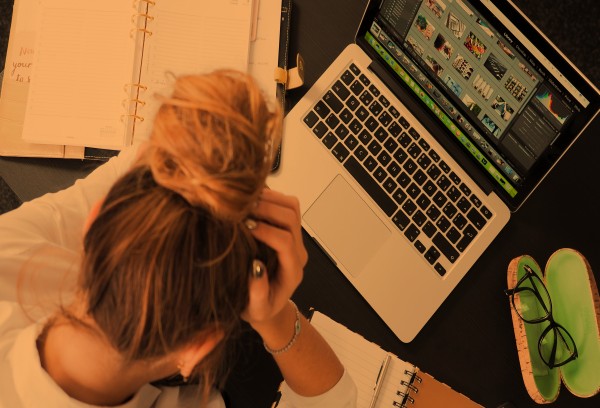Foto van een vrouw die balend achter haar laptop zit vanwege een veroorzaakt datalek.