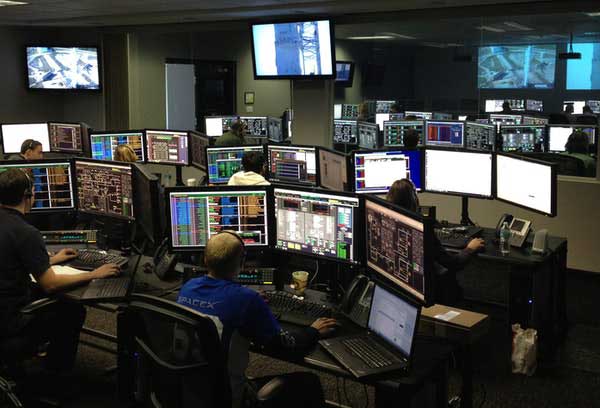 Afbeelding van een ruimte met computers met medewerkers die daarop werken.