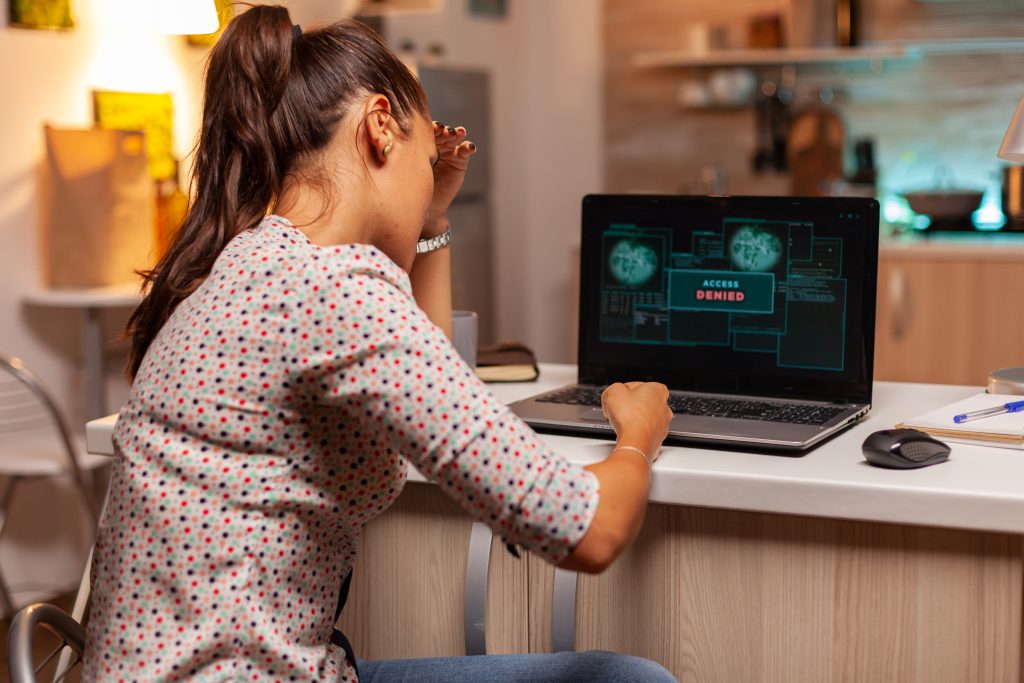 Een foto van een vrouwelijke medewerker zittend achter een bureau met een computer. Het systeem is overgenomen en de hacker heeft toegang tot de organisatie. 